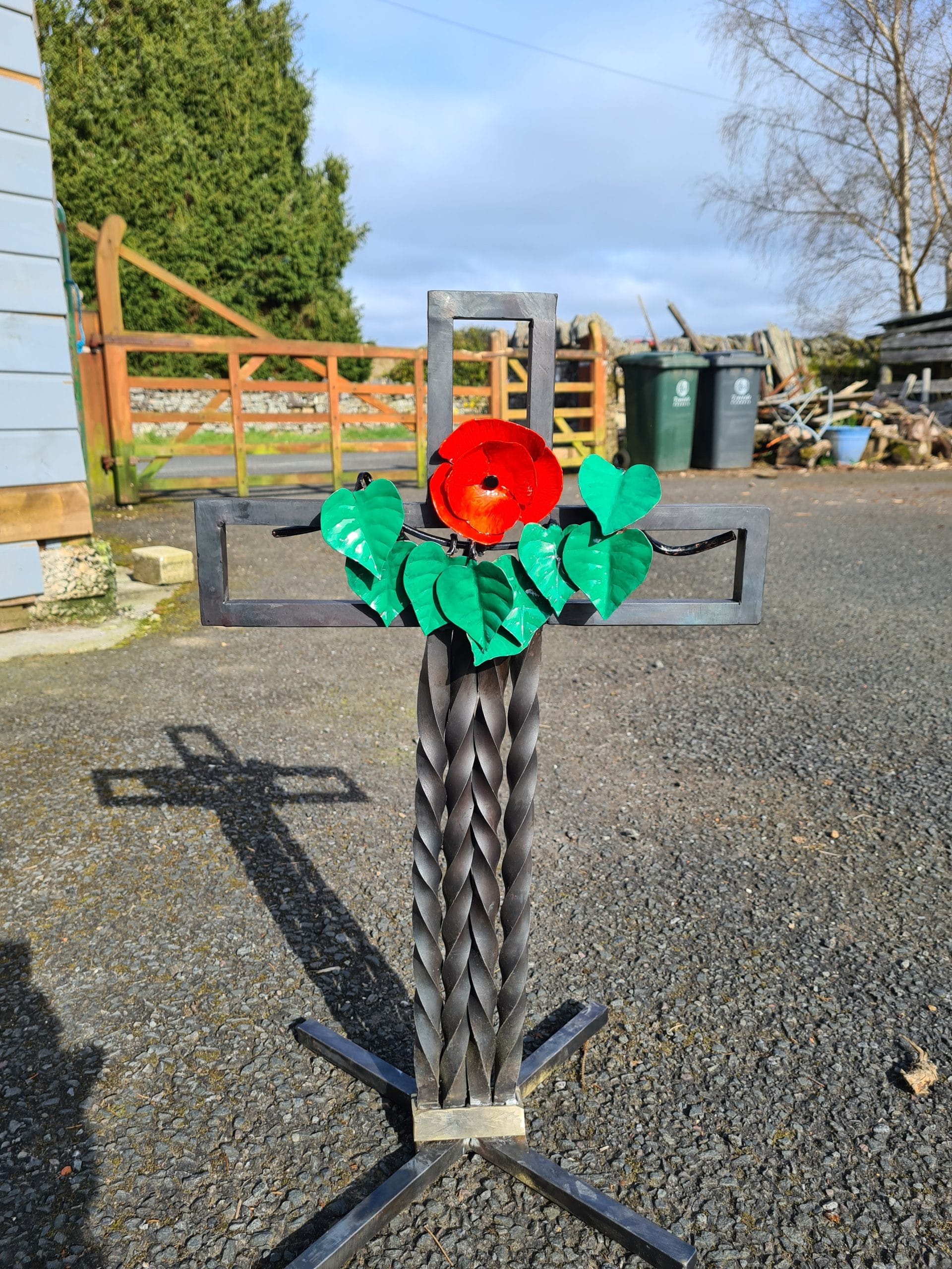 St Peters Church Cross Metal cross with red flower in yard
